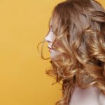 Beautiful redheaded girl with luxurious curly hair. Portrait in profile. Free space left.